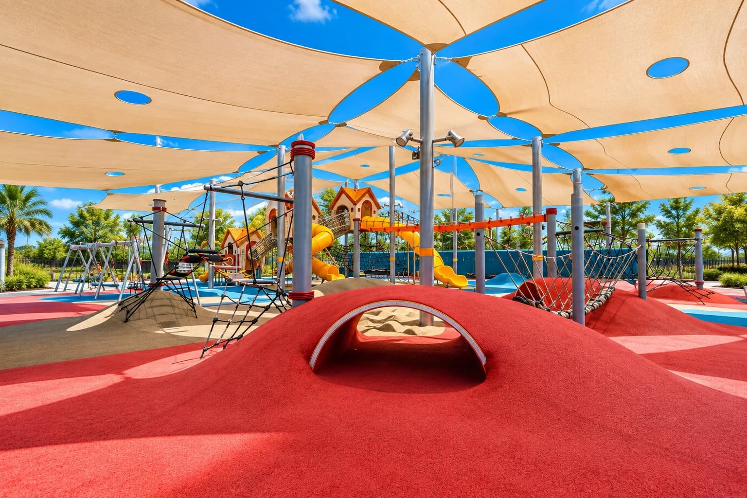 Flower-shaped shade sails covering a red rubber-surfaced playground with climbing nets and slides.