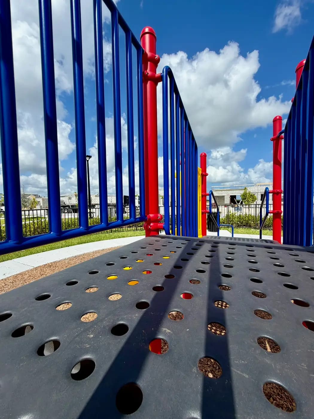 Red and blue playground posts with an overhead climber at Acacia Groves