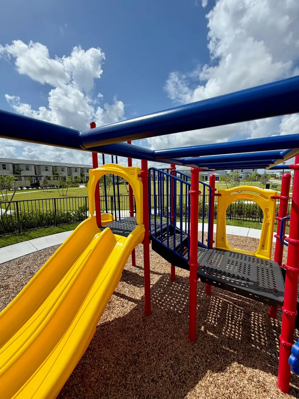 Play deck with double yellow slide and overhead beams at Acacia Groves