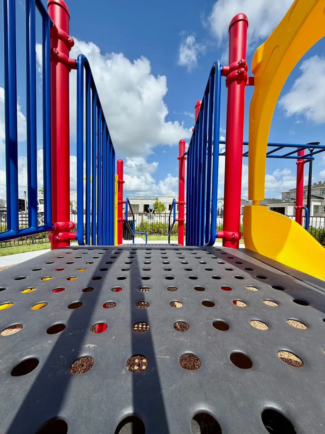 Play system with yellow slides framed by red and blue posts at Acacia Groves