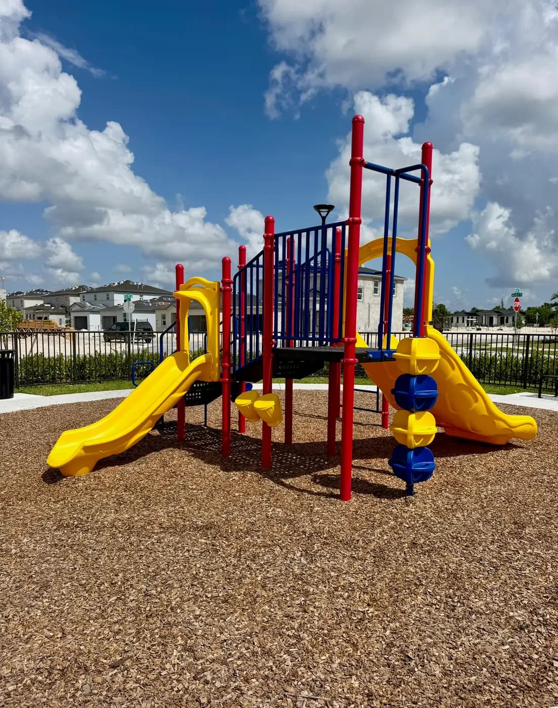 Red, blue and yellow play system with twin yellow slides on engineered wood fiber