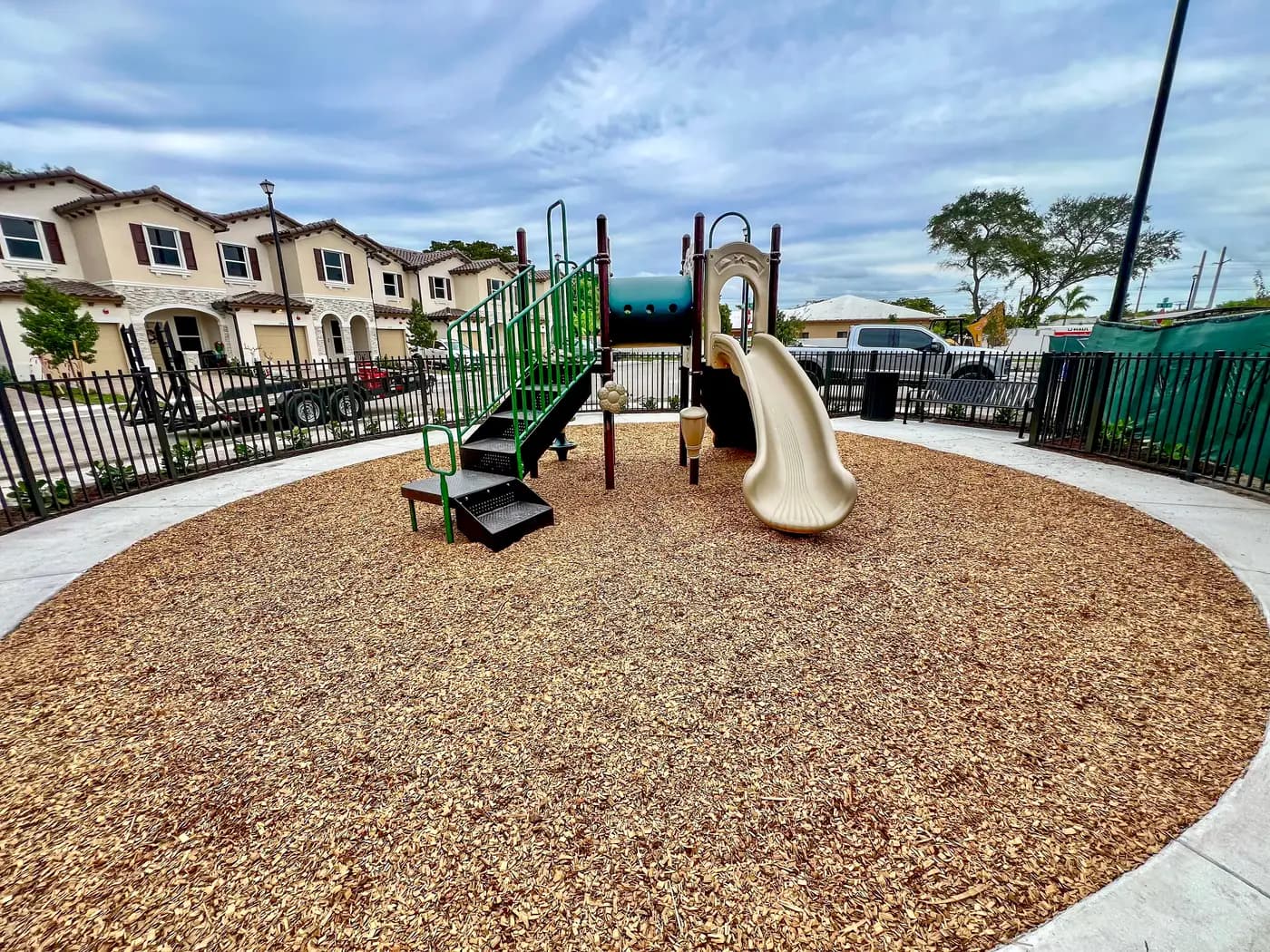 Compact green and tan play structure beside townhomes at Azalea