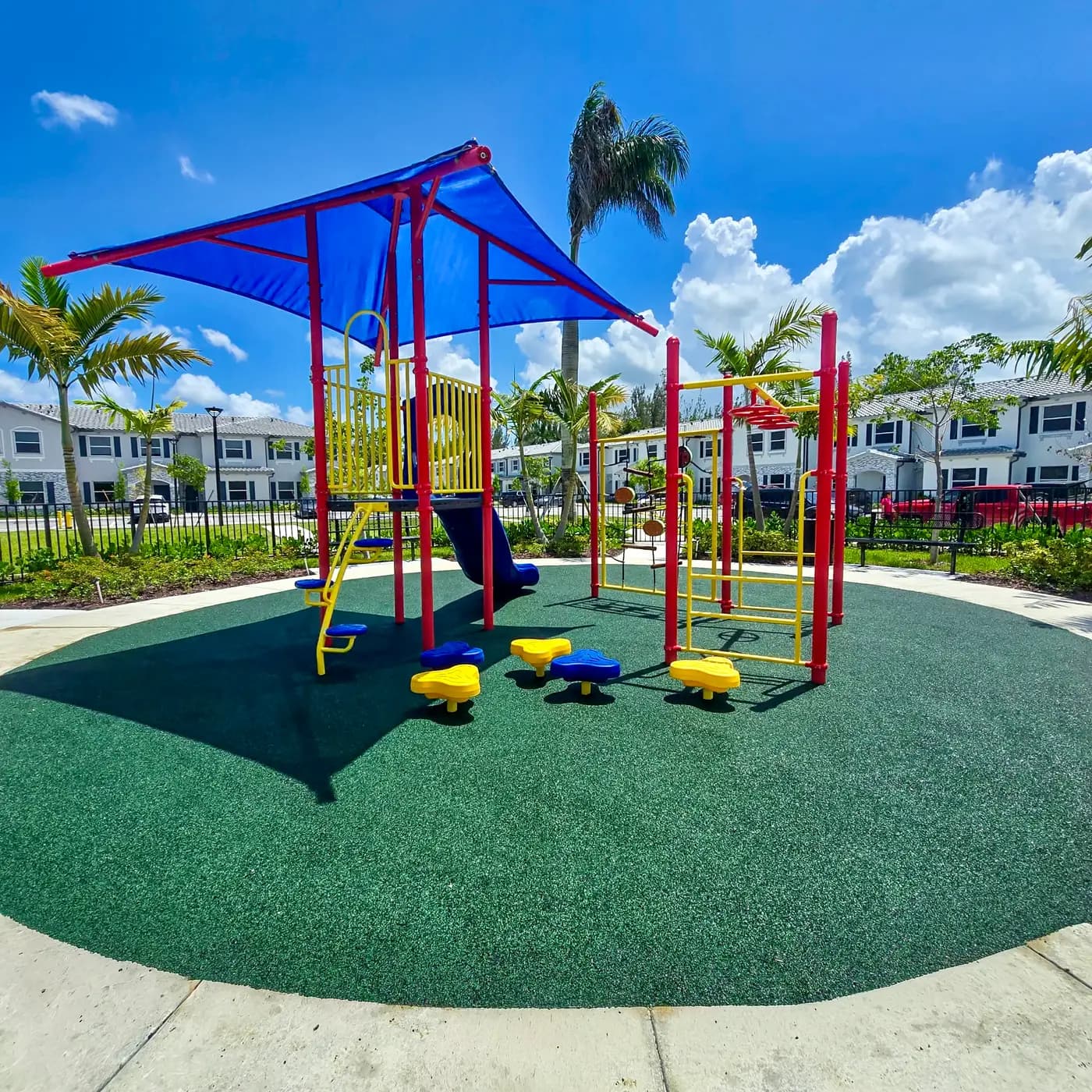 Play system under blue shade sails on poured-in-place rubber
