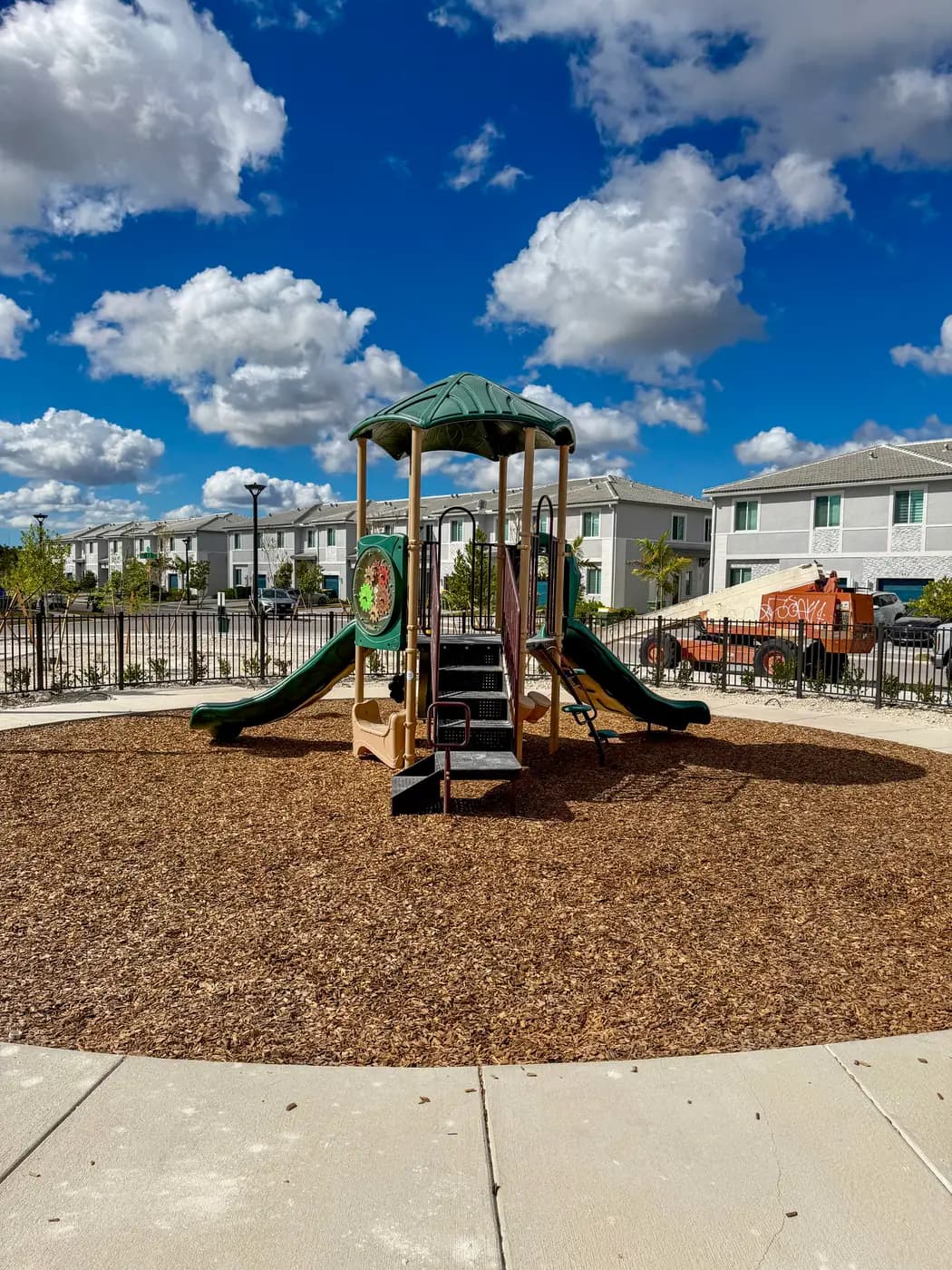 Green and tan play structure with twin slides at Terra Sol