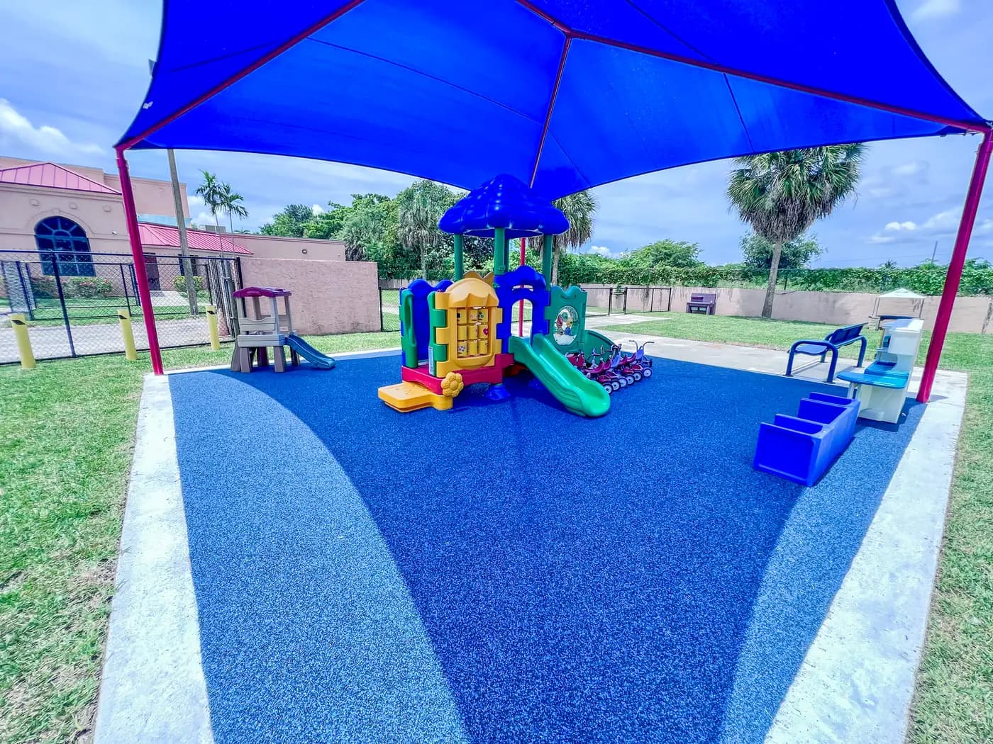 Colorful tot lot unit on blue poured-in-place rubber under the shade canopy