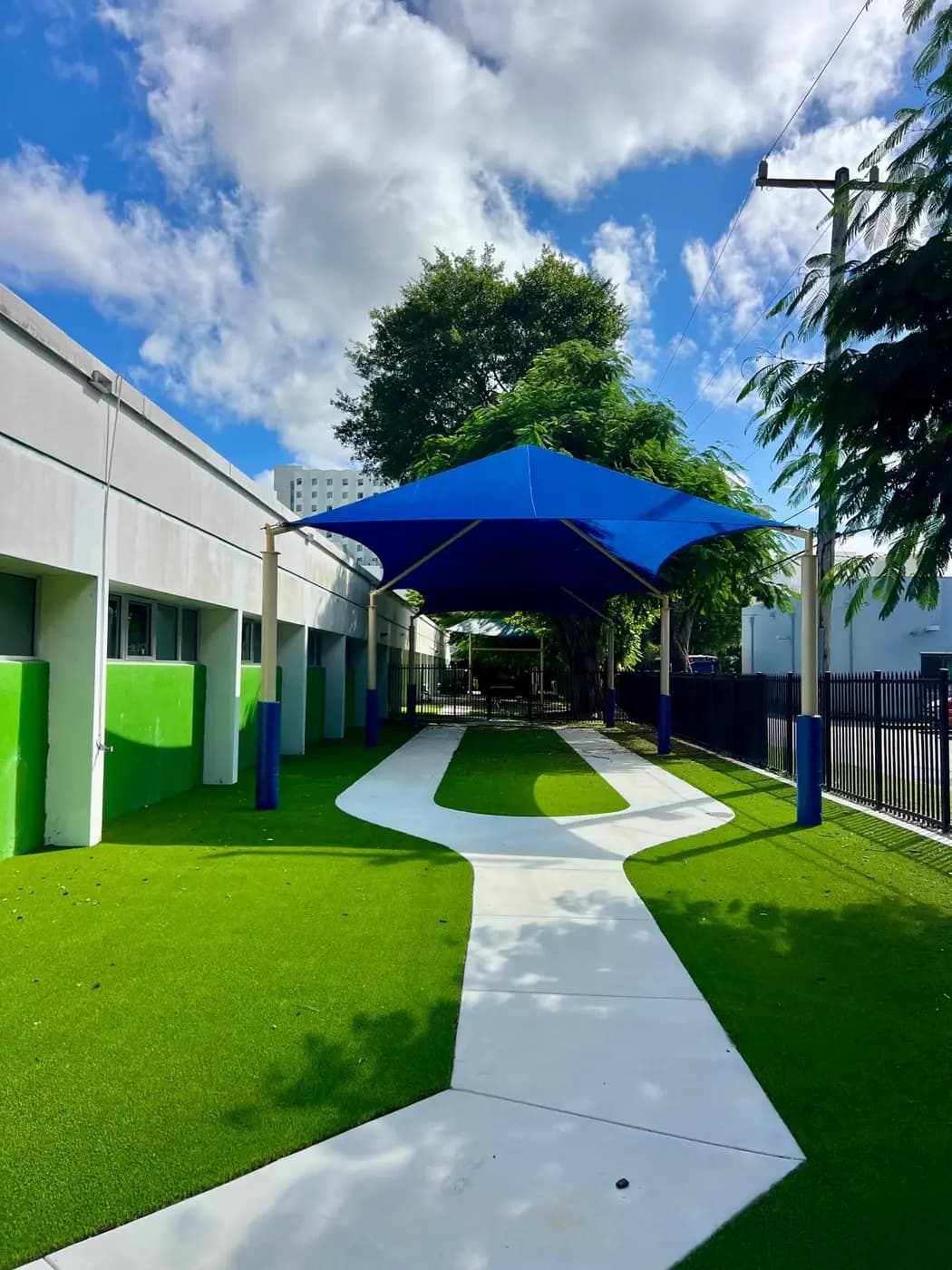 Double hip shade covering the walkway of a green and white school building