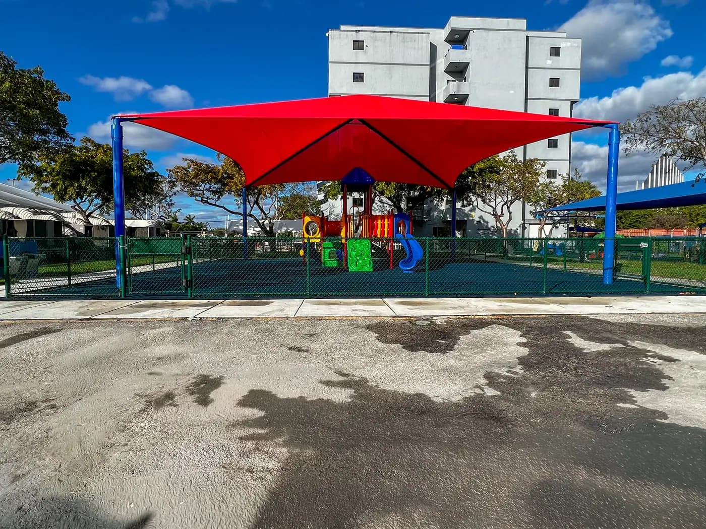 Large red hip shade covering an entire fenced playground