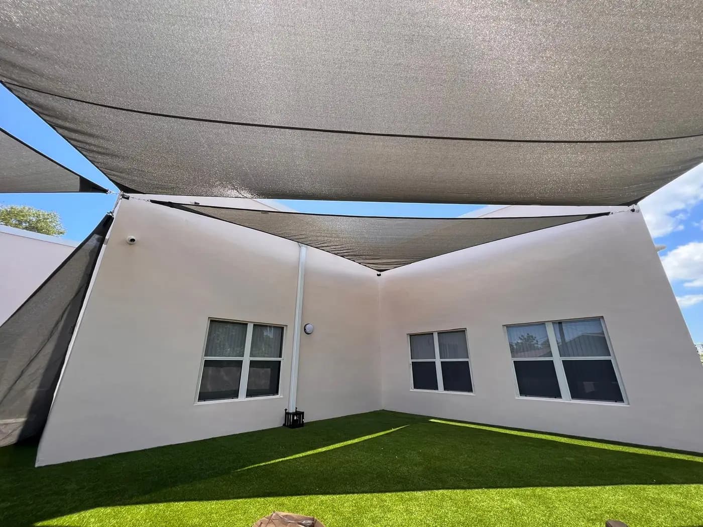 Shade sails over the artificial turf yard of a daycare