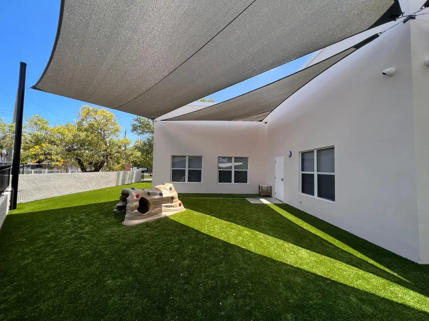 Overlapping shade sails above a daycare turf yard