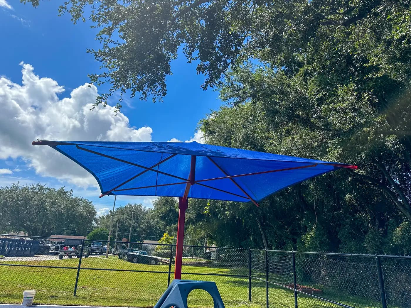 Blue single post cantilever shade with a red frame at a playground