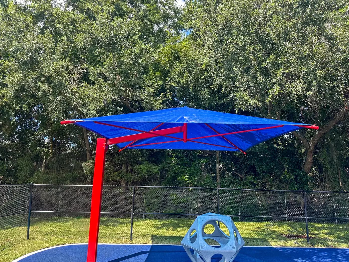 Blue single post cantilever shade beside a fenced play area
