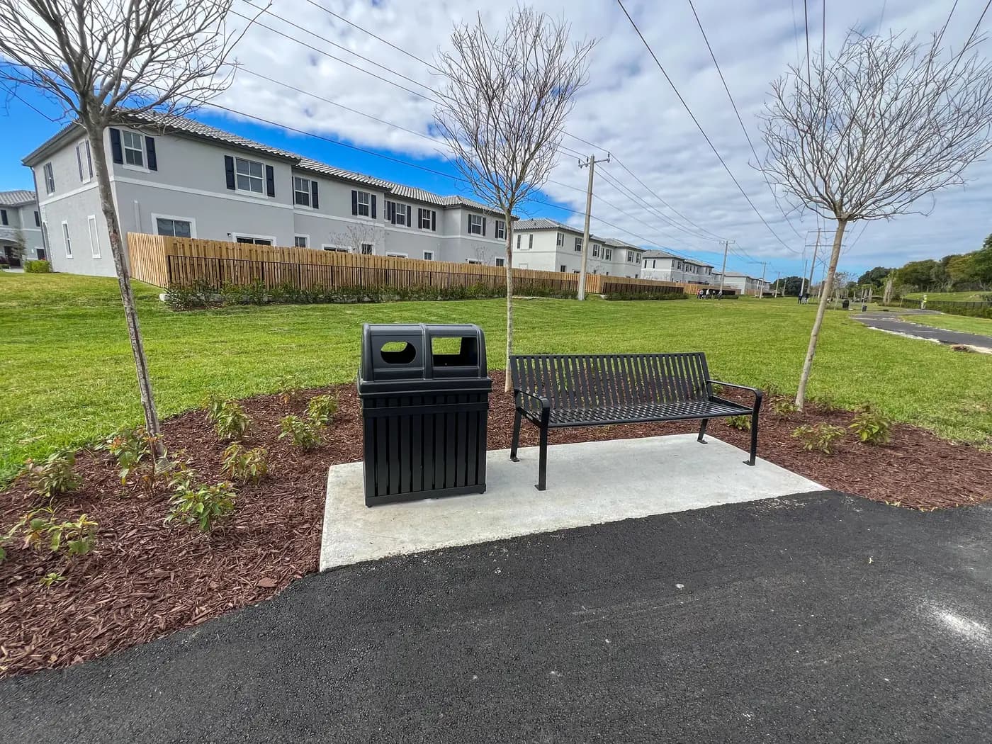 Metal bench and trash receptacle on a concrete pad at a new community