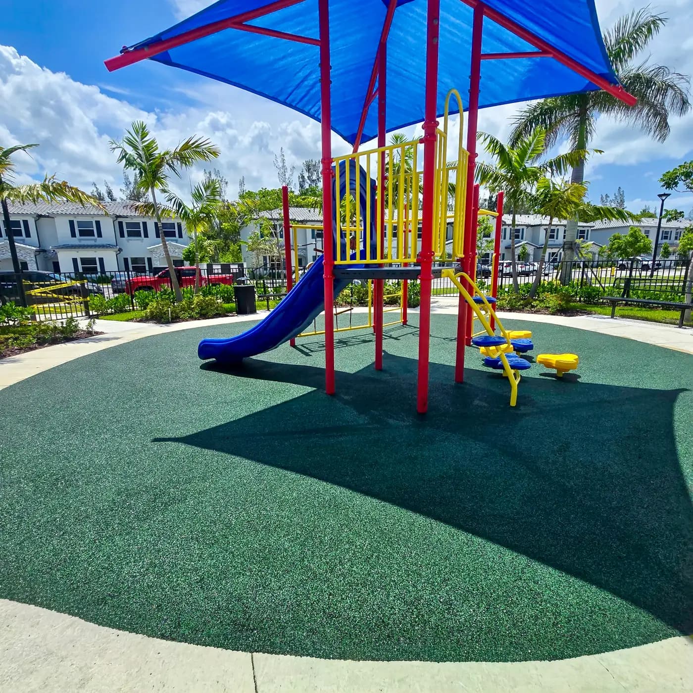 Blue slide and yellow play elements beneath the Le Jardine shade sails