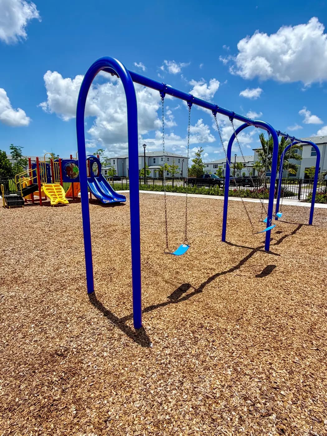 Blue arched swing set beside the toddler play unit at Vivant
