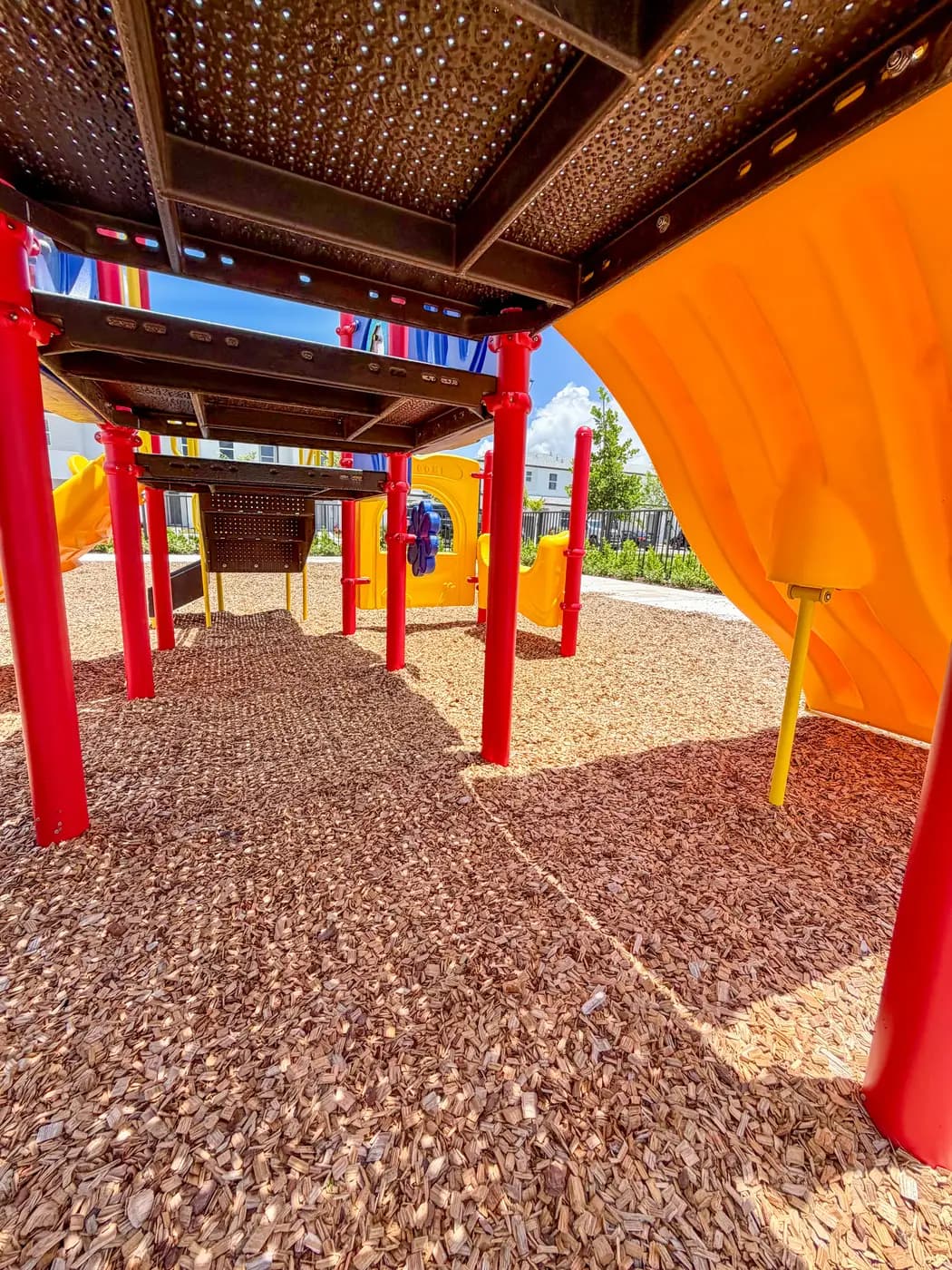 View beneath the play deck of the Vivant play system with an orange slide